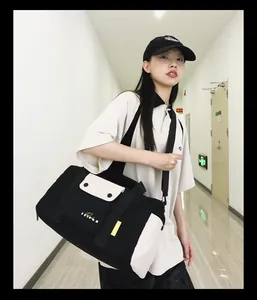 Grand sac de sport et de voyage noir et blanc porté par une personne dans un couloir