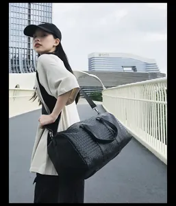 Mannequin asiatique portant un grand sac de voyage tissé noir sur un pont extérieur