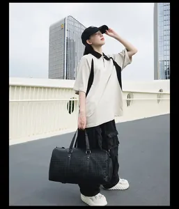 Mannequin portant un grand sac de voyage tissé noir sur fond de paysage urbain