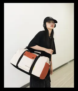 Modèle portant un grand sac de voyage blanc avec des détails orange et noirs.