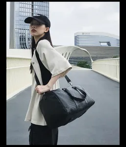 Mannequin asiatique portant un grand sac de voyage noir tressé dans un décor urbain