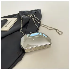 Close-up van een zilveren metalen geometrische avondtas met kettingriem op een blazer