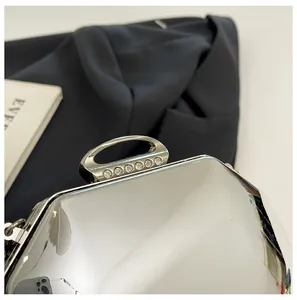 Detailopname van een zilveren metallic avondtas met een ovale sluiting versierd met kristallen
