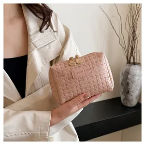Minimalist pink quilted square cosmetic clutch bag being held by a model in detail view