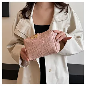 Detailed view of a stylish pink woven cosmetic bag held by a woman in a white coat