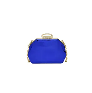 Detail van een kobaltblauwe zeshoekige avondclutch met gouden ketting en strass-sluiting