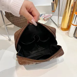 Interior detail of a stylish woven brown makeup bag showing multiple functional pockets