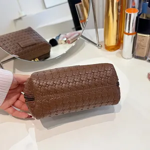 Detailed view of the elegant brown Intrecciato woven pattern on a portable makeup pouch.