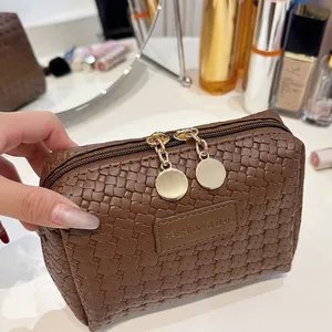 Detail of a brown woven cosmetic bag with "FASHION & BAG" label and gold zippers.