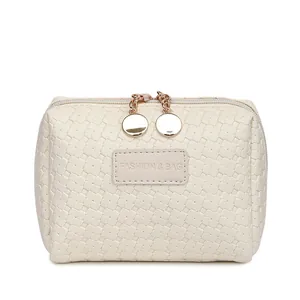 Close-up of cream woven checkered cosmetic bag with gold zippers and brand patch