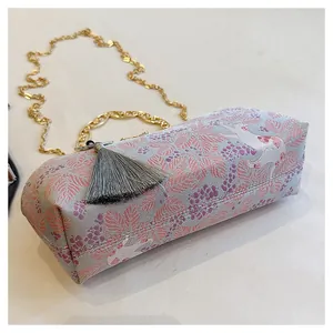 Close-up detail of embroidered evening clutch with tassel and gold chain strap