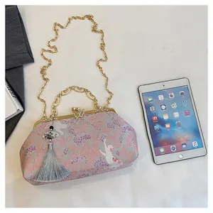 Detailed view of pink embroidered evening bag with tassel and butterfly clasp