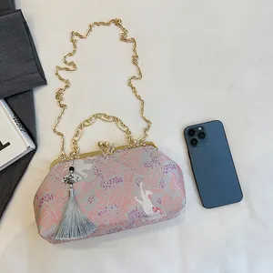 Detail of embroidered evening bag with cat pattern, butterfly clasp and elegant tassel.