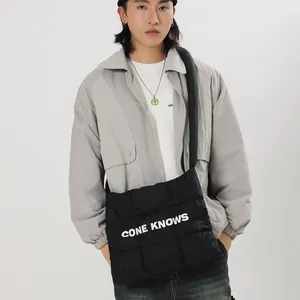 Sac fourre-tout matelassé noir tendance avec imprimé de lettres blanches porté par un mannequin
