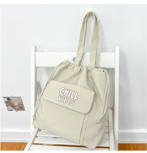 Detailopname van een grote crème nylon draagtas met "CHILL VIBES" print op een stoel.