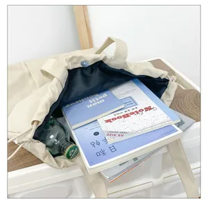 Binnenaanzicht van beige nylon draagtas met grote capaciteit, boeken en een flesje water