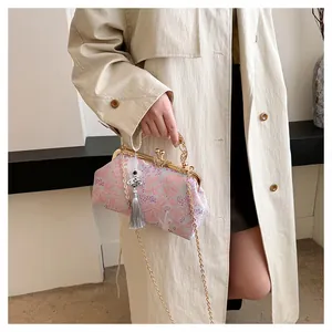 Detailed view of an elegant embroidered evening bag with tassel and butterfly clasp