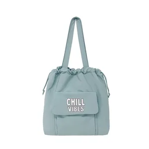 Lichtblauwe nylon tote bag met trekkoord en Chill Vibes tekst op de voorzak flap.