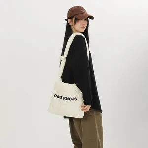 Détail du sac fourre-tout en nylon matelassé crème avec imprimé de lettres CONE KNOWS noir.