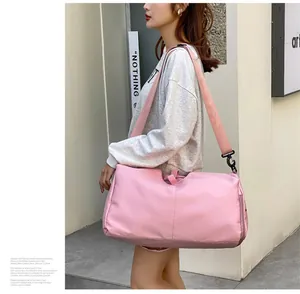 Asiatisches Modell trägt eine große rosa Oxford-Sporttasche für Fitness oder Reisen