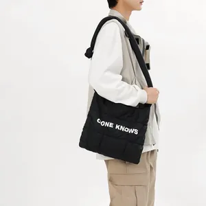 Modèle portant un sac cabas en nylon matelassé noir avec imprimé de lettres blanches