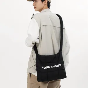 Sac bandoulière décontracté en nylon matelassé noir avec imprimé de lettres blanches.