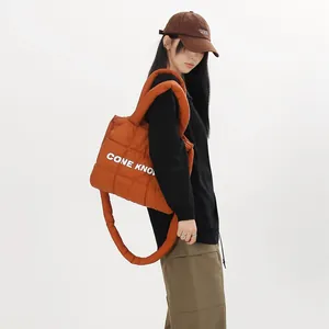 Gros plan d'un sac cabas rembourré en nylon orange matelassé porté par un mannequin