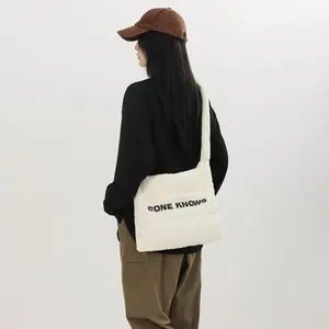 Modèle portant un sac fourre-tout matelassé blanc élégant avec imprimé lettres.