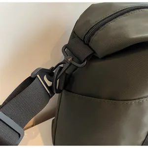 Close-up detail of durable fabric and strap hook on an olive green travel duffel bag