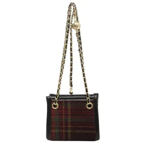 Detail view of a plaid wool crossbody bag with a golden chain strap and ball detail.