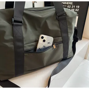 Detail view of olive green travel bag featuring a front zipper pocket with a smartphone.