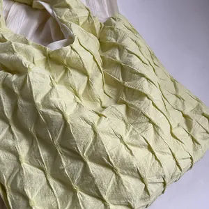 Close-up detail showing the unique diamond pleated texture of this yellow tote bag