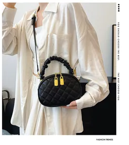 Close-up of a black quilted handbag with a ruffled handle shown on a fashion model