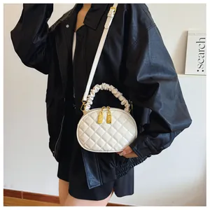 Stylish model carrying a white quilted handbag featuring a ruffled handle and gold hardware.