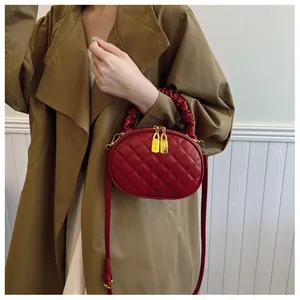 Close-up of red quilted handbag with golden lock zippers and scrunchie handle
