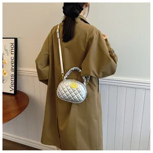 Silver quilted handbag with scrunchie handle worn with a stylish brown trench coat
