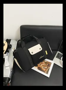 Sac de sport noir et blanc posé sur un siège à côté d'un ordinateur et d'un magazine