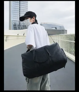 Mannequin asiatique portant un grand sac de voyage tissé noir sur un pont piétonnier