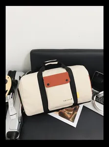 Sac de voyage beige et noir présenté sur une chaise avec accessoires