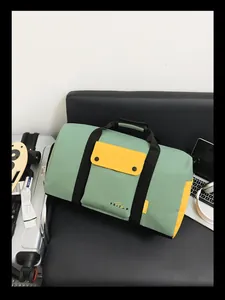 Vue détaillée d'un sac de voyage élégant vert et jaune sur un canapé en cuir noir