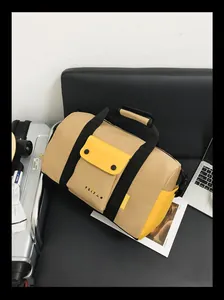 Détail du sac de voyage kaki et jaune avec poche à rabat frontale et logo imprimé.