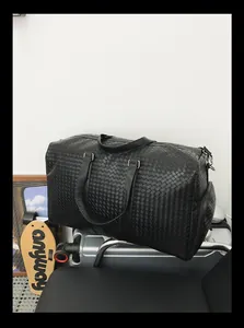 Vue détaillée du sac de voyage noir tressé montrant la texture et le style de design