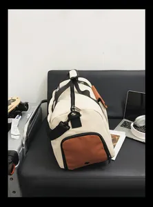 Vue détaillée de face du grand sac de voyage crème et marron sur canapé en cuir