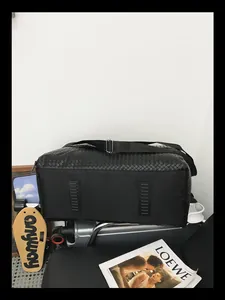 Vue détaillée du dessous d'un grand sac de voyage tissé noir avec des rails de protection à la base.
