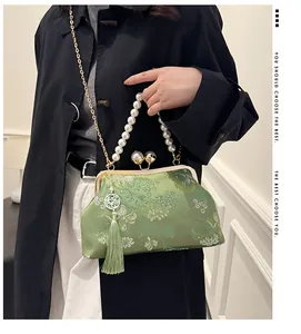 Elegante bolso bordado verde con asa de perlas y borla de seda mostrado en un detalle de moda