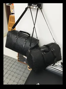 Gros plan de deux sacs de voyage en cuir tressé noir suspendus de tailles différentes