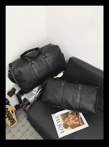 Gros plan de sacs de voyage en cuir tressé noir avec une texture premium.