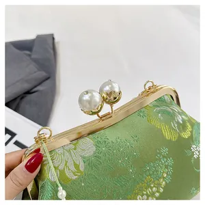 Detalle exquisito de bordado chino verde en un bolso con cierre de perlas grandes