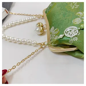 Primer plano detallado de bolso bordado verde vintage con asa de perlas y cadena