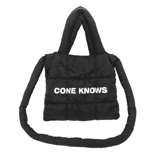 Détail du sac cabas matelassé noir avec texture rembourrée et impression de texte.